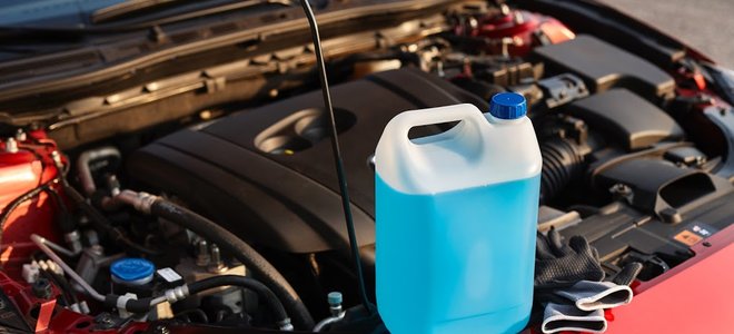 container of antifreeze sitting near car engine